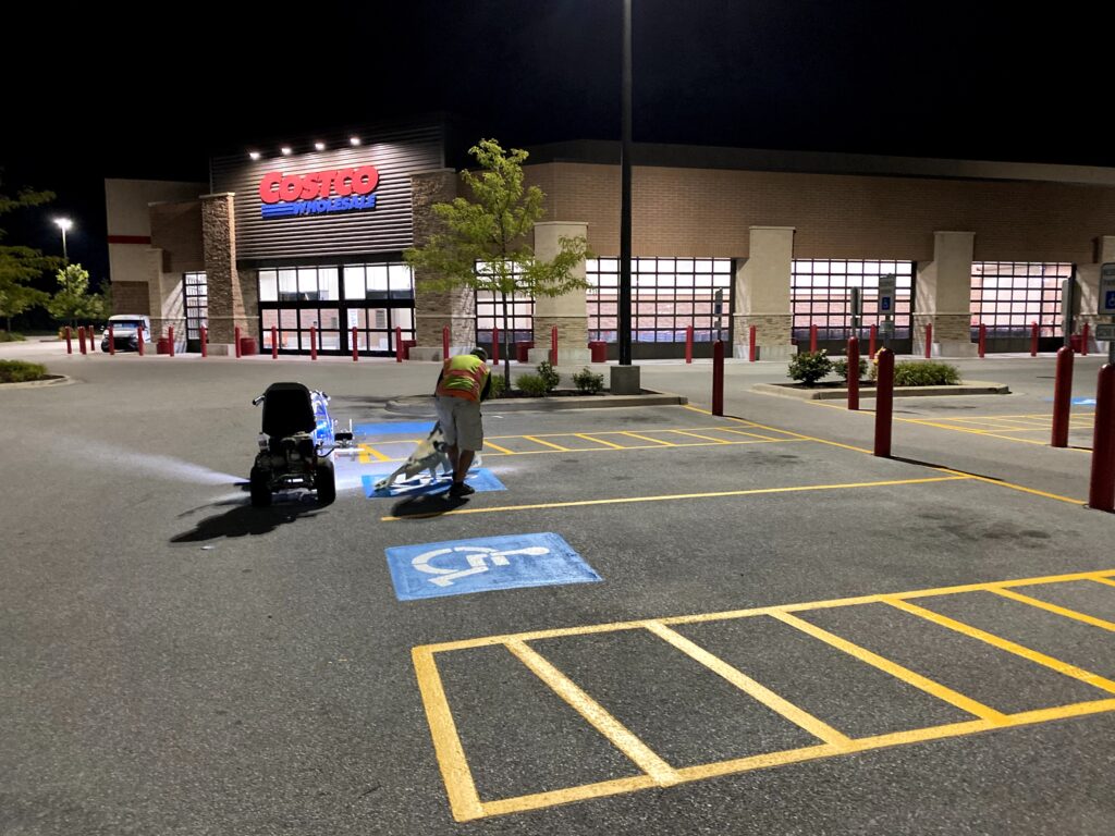 Costco Wholesale building illuminated at night, featuring empty parking spaces with marked handicapped and van-accessible spots.