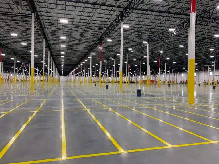 Professional contractor applying durable epoxy line striping on a warehouse floor to ensure clear pathways